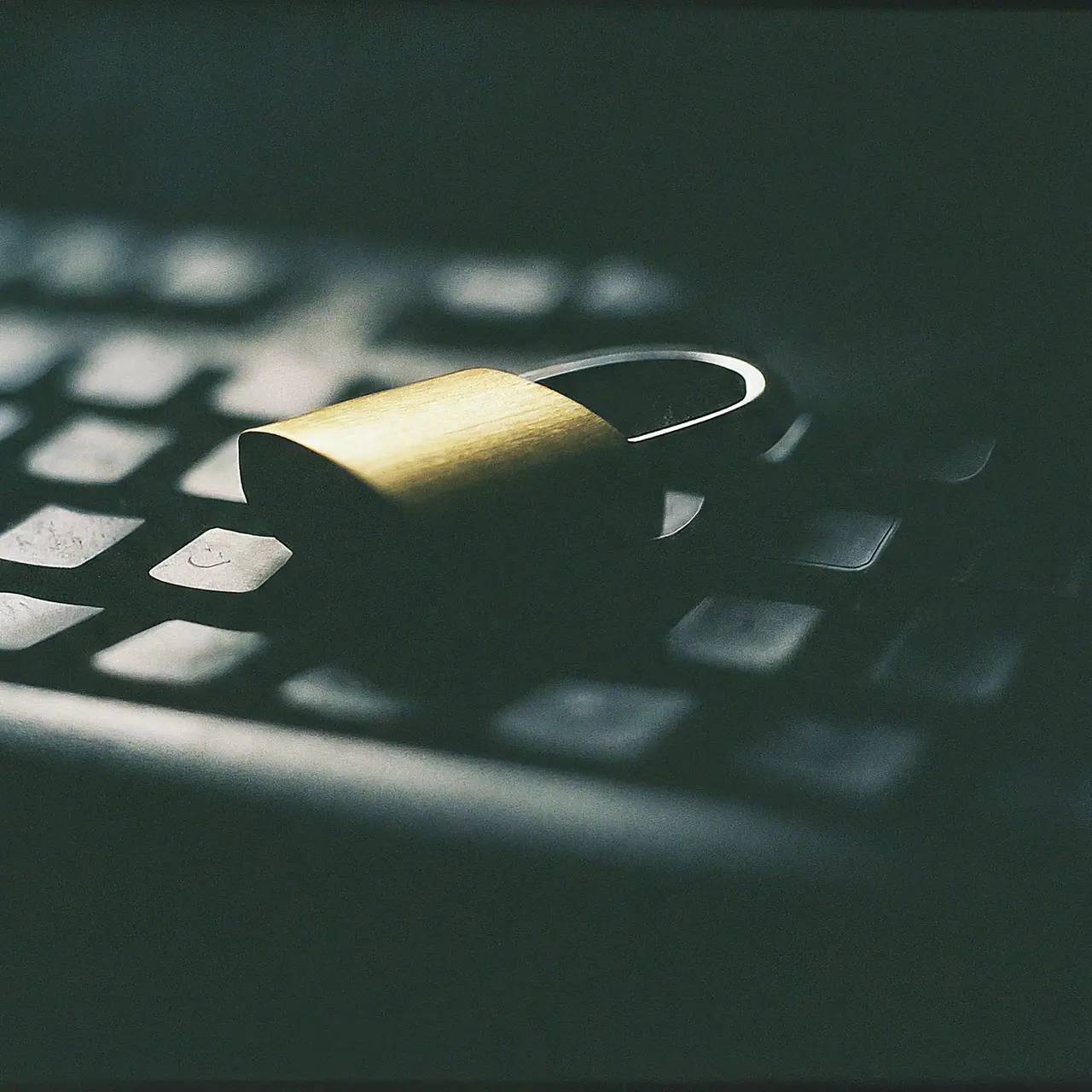 A padlock on a computer keyboard in dim lighting. 35mm stock photo