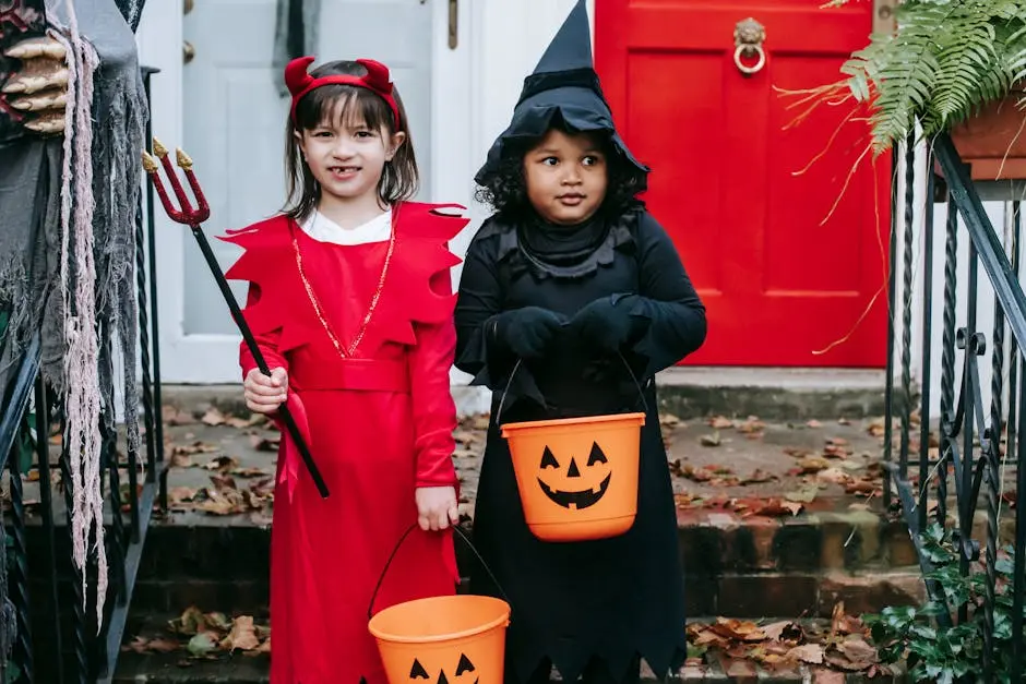 Diverse preschool girlfriends in costumes holding buckets and trident while standing near door on Halloween