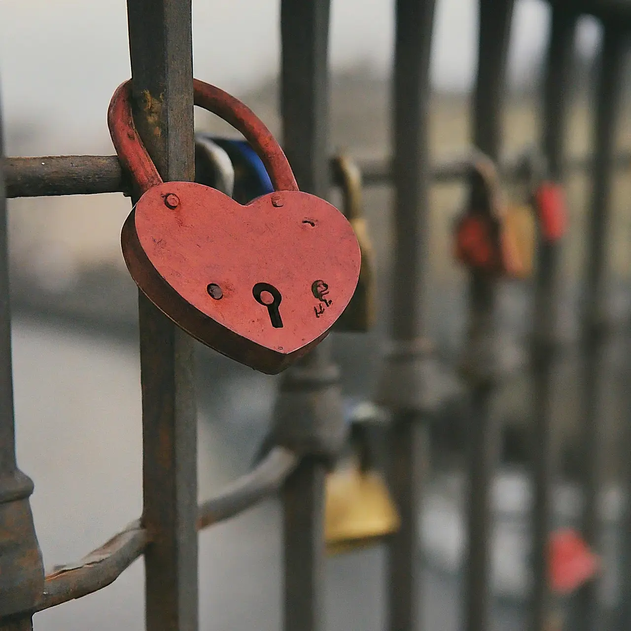 A heart-shaped padlock hanging on a bridge railing. 35mm stock photo