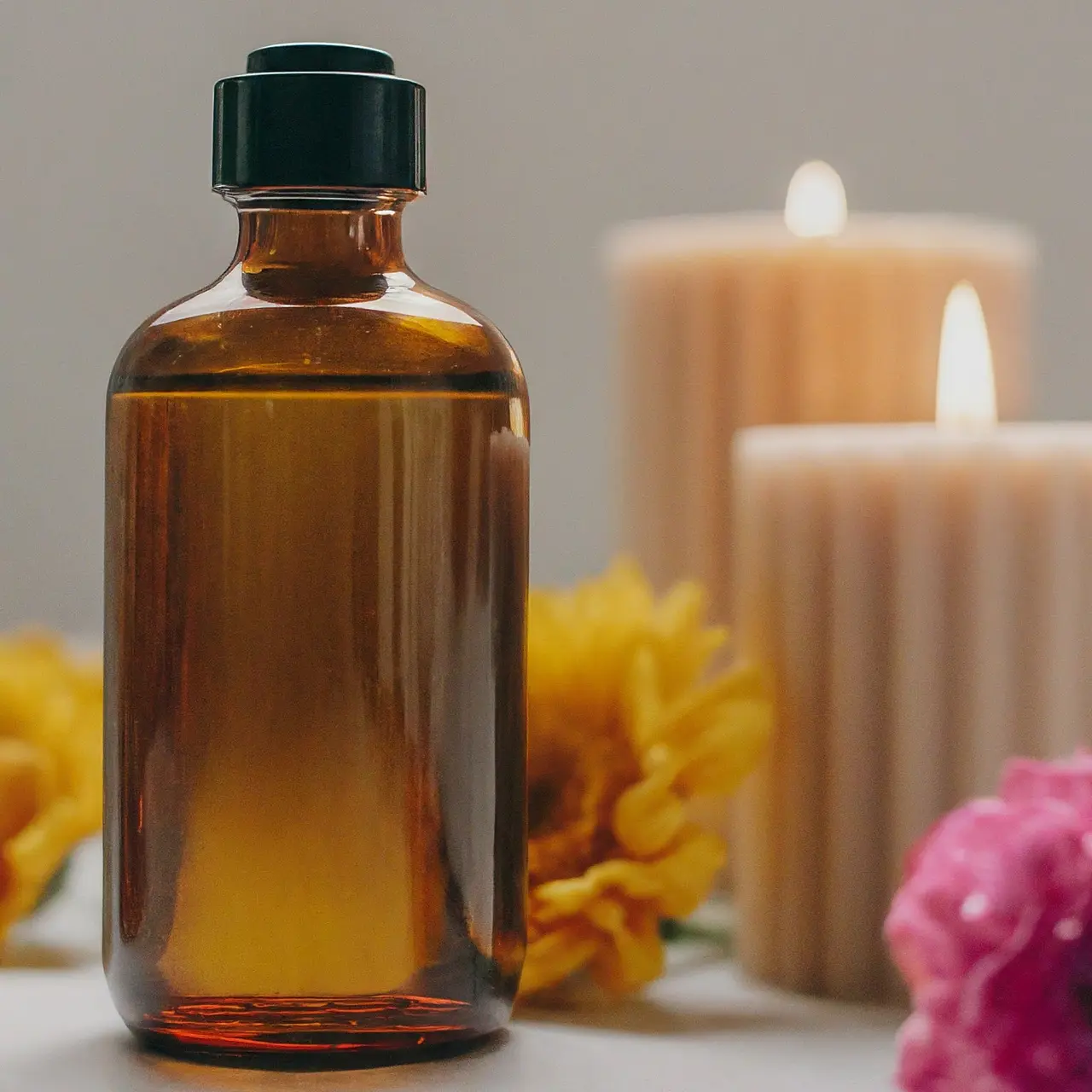 A bottle of bath oil next to candles and flowers. 35mm stock photo