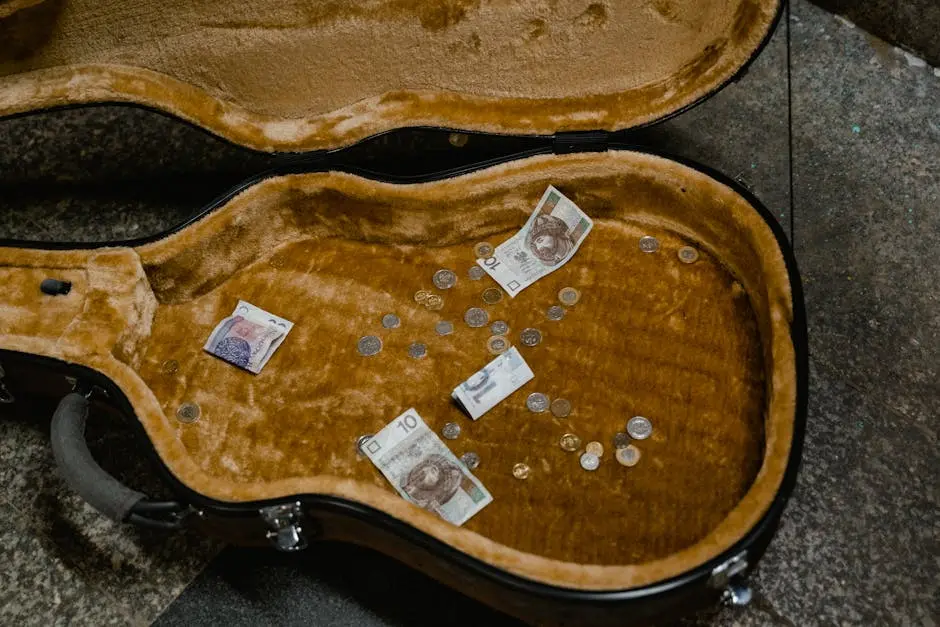 Open guitar case filled with various currencies and coins from street performance.