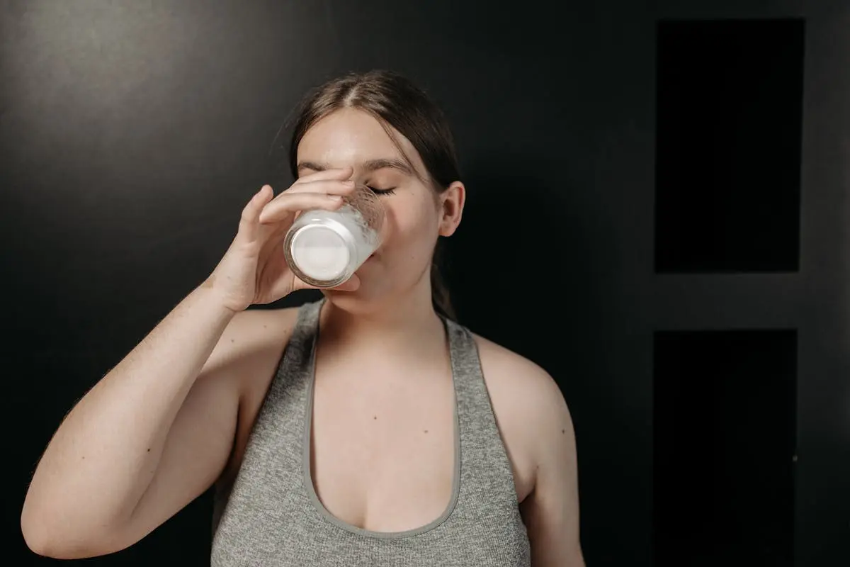 Woman Wearing Gray Tank Top Drinking Milk