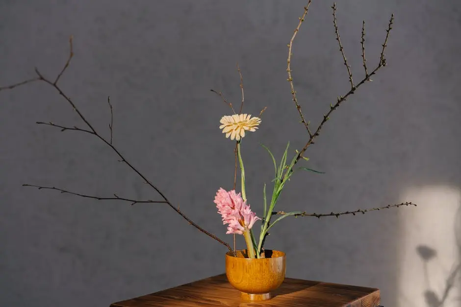 A minimalist floral arrangement in a wooden vase with branches and soft lighting.