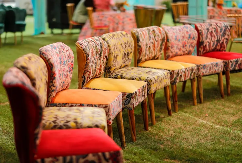 A row of vibrant, patterned chairs arranged outside on a lawn, perfect for events.