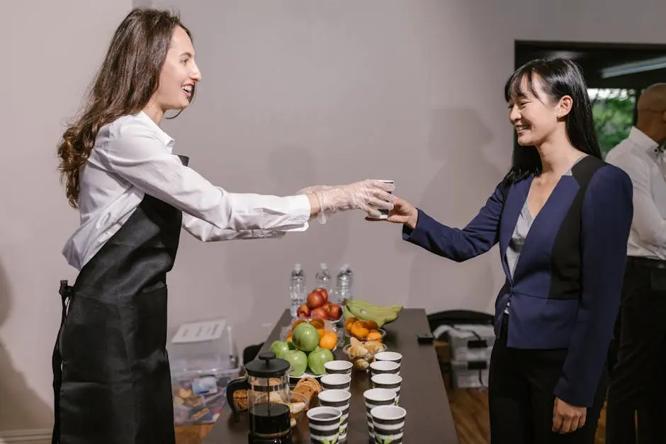 Two professionals interacting at a catered business event with coffee and fruit.