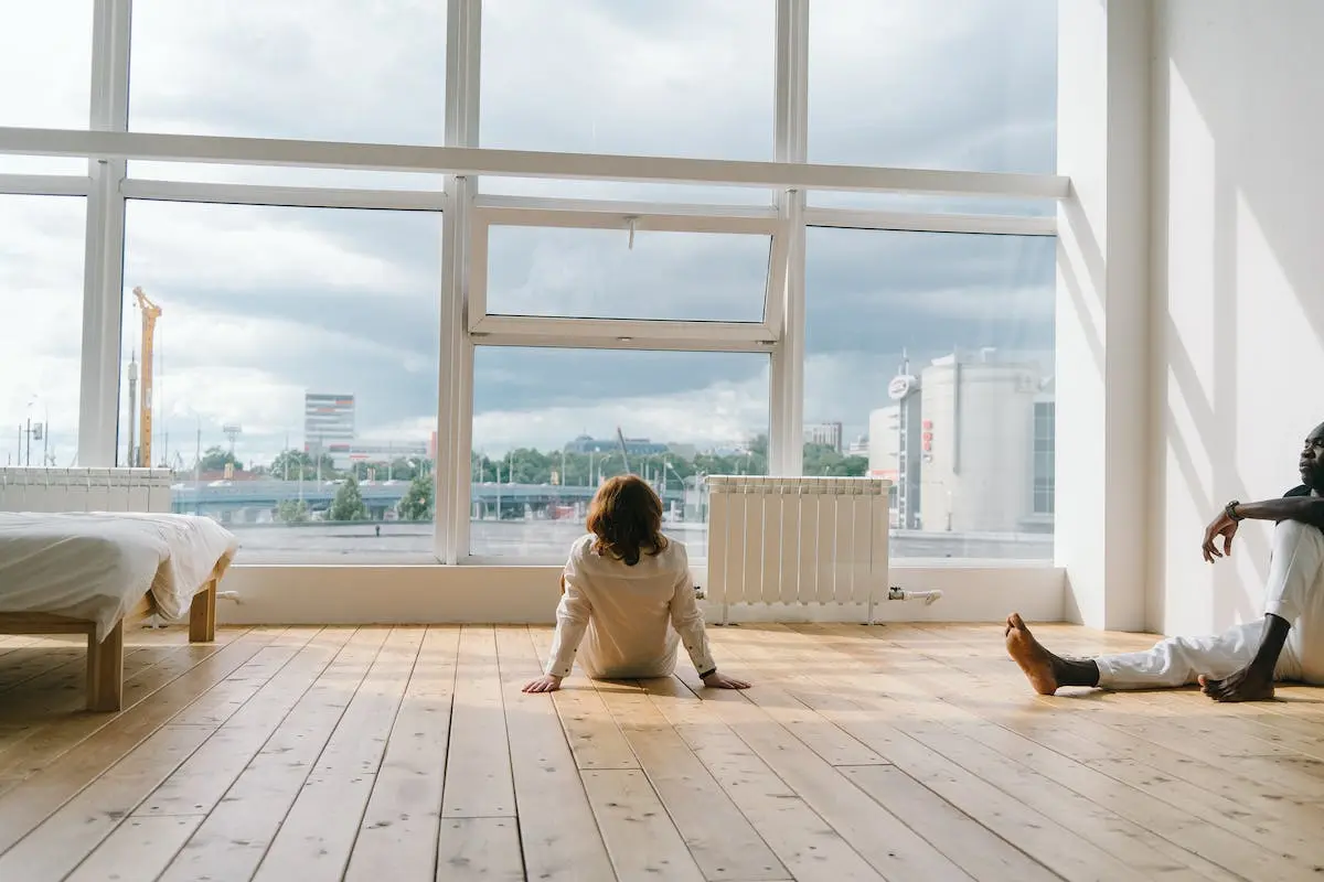 Woman in White Long Sleeve Shirt Sitting on Brown Wooden Floor