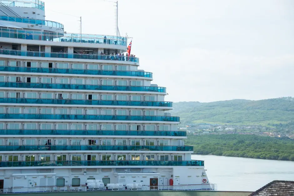 Luxury cruise ship with balconies docked by a lush green coastline, ideal for travel imagery.