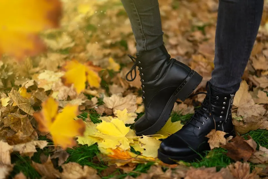 A Person in Black Leather Boots Standing on Autumn Leaves