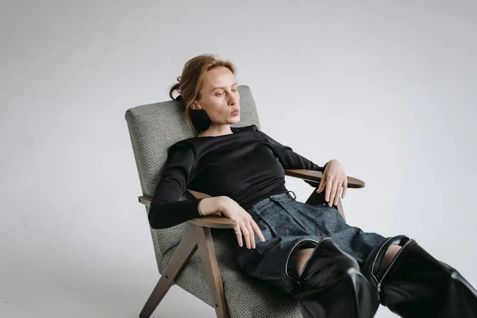 Individual relaxing in a stylish armchair wearing black and denim, exuding modern comfort.