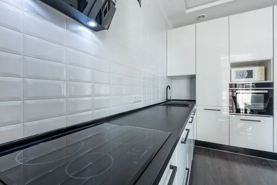 Interior of modern light white kitchen furnished with white cupboards and appliances with wooden floor and tiled wall