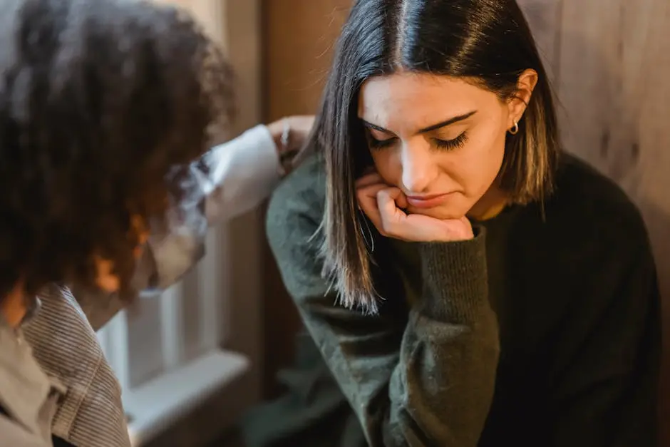 Crop woman tapping shoulder and comforting upset female friend while sitting at home together