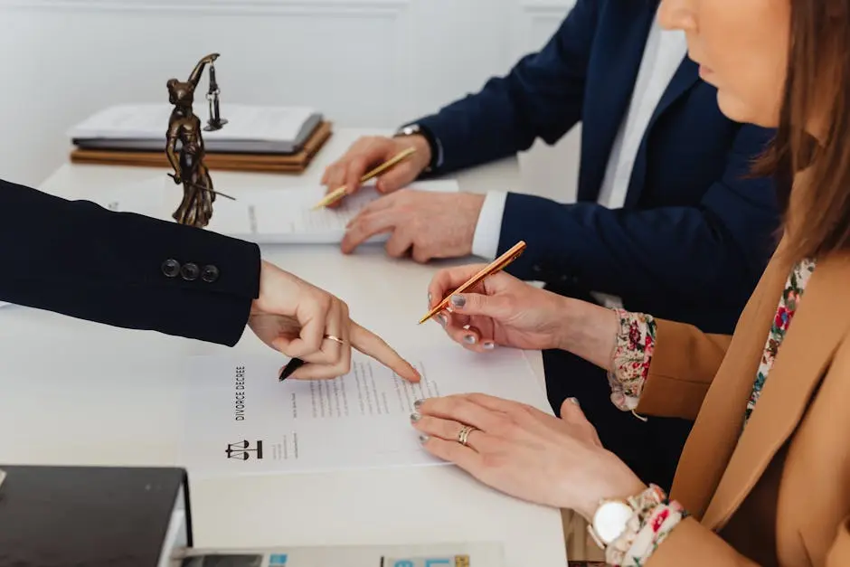 Hands signing a divorce decree, with a justice statue nearby, symbolizing legal proceedings.