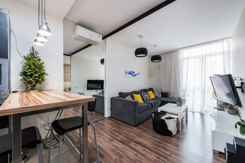 Interior of modern spacious living room with comfy sofa and wooden counter placed near big mirror reflecting TV in daytime