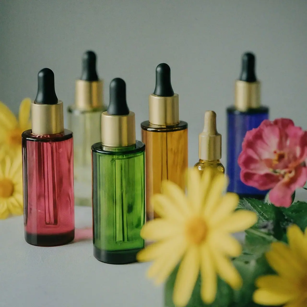 A collection of colorful essential oil bottles with fresh flowers. 35mm stock photo