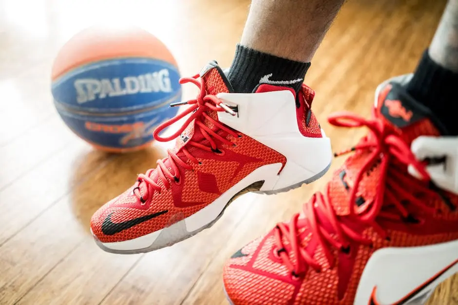 Close-up of red basketball sneakers in action with a Spalding ball on wooden floor.