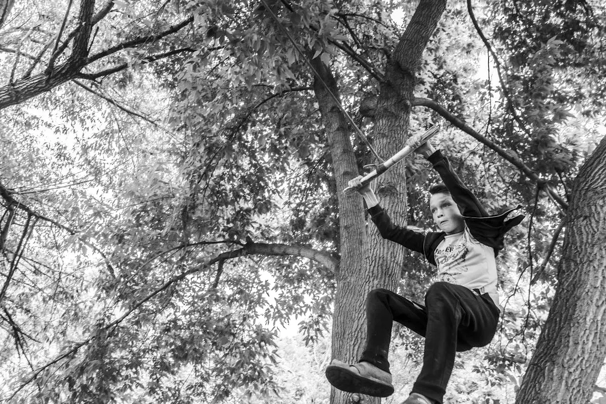 A boy swinging on a trapeze bar outdoors, capturing childhood joy and adventure.