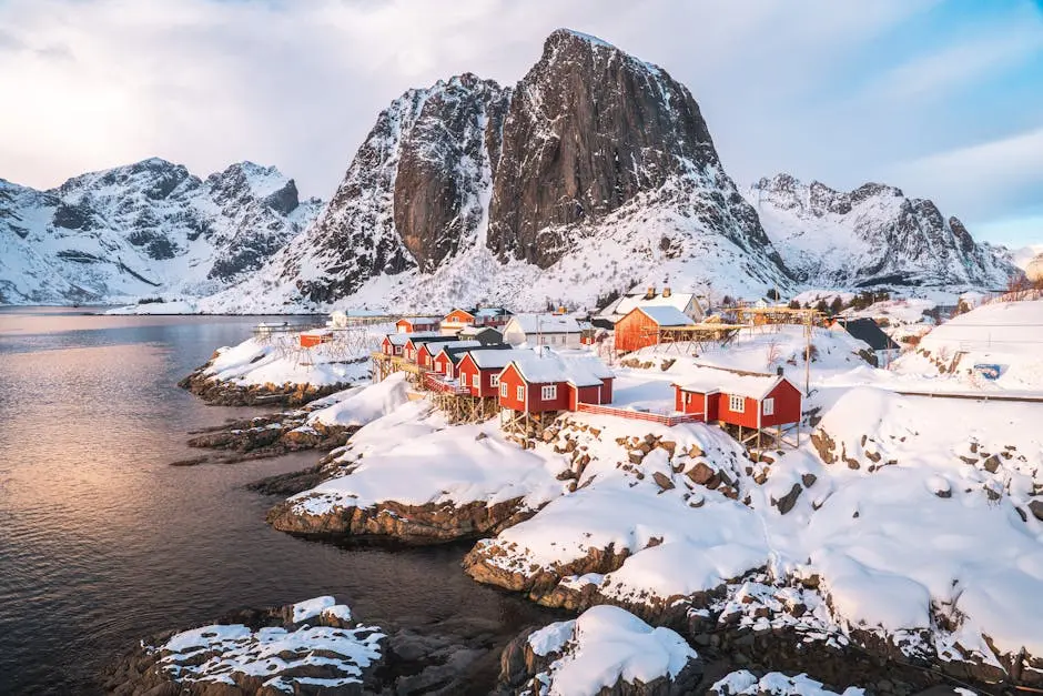 A breathtaking aerial view of snow-covered Hamnøy village, framed by mountains and the sea in winter.