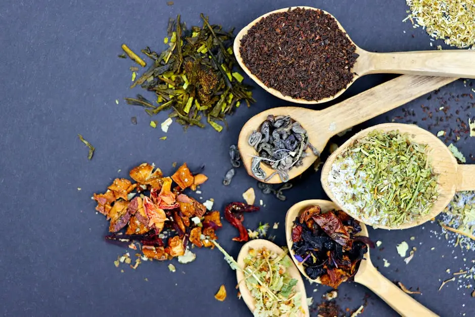 Top view of various herbal tea blends displayed on wooden spoons, showcasing a mix of textures and colors.