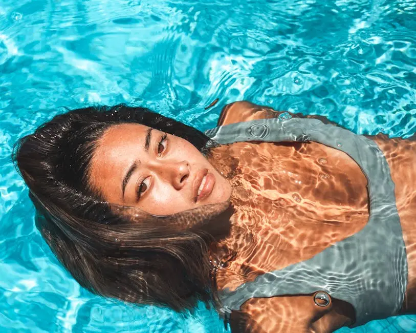 Close-up of a woman relaxing in a clear blue swimming pool under bright sunlight.