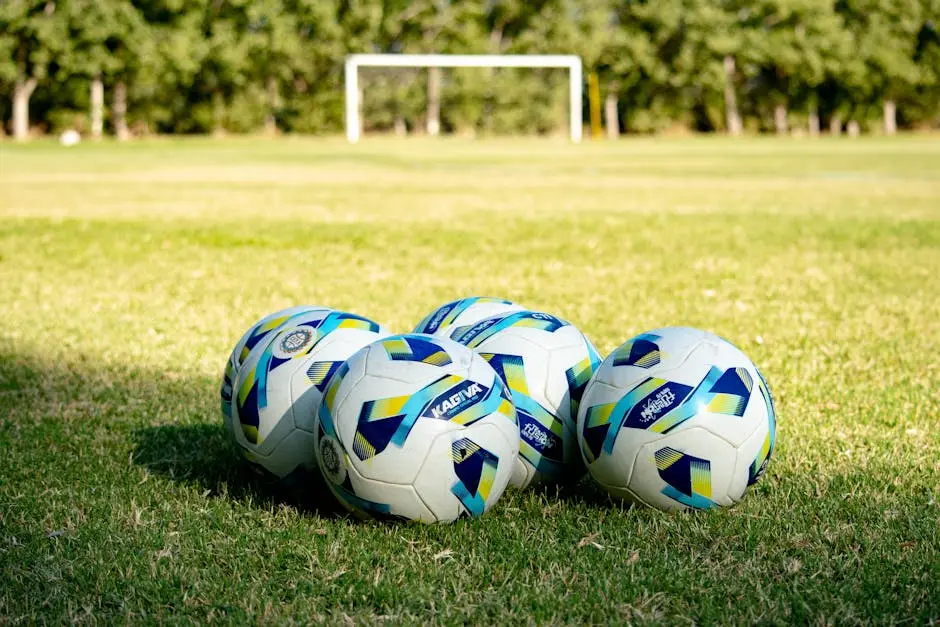 Three soccer balls on the grass in front of a goal