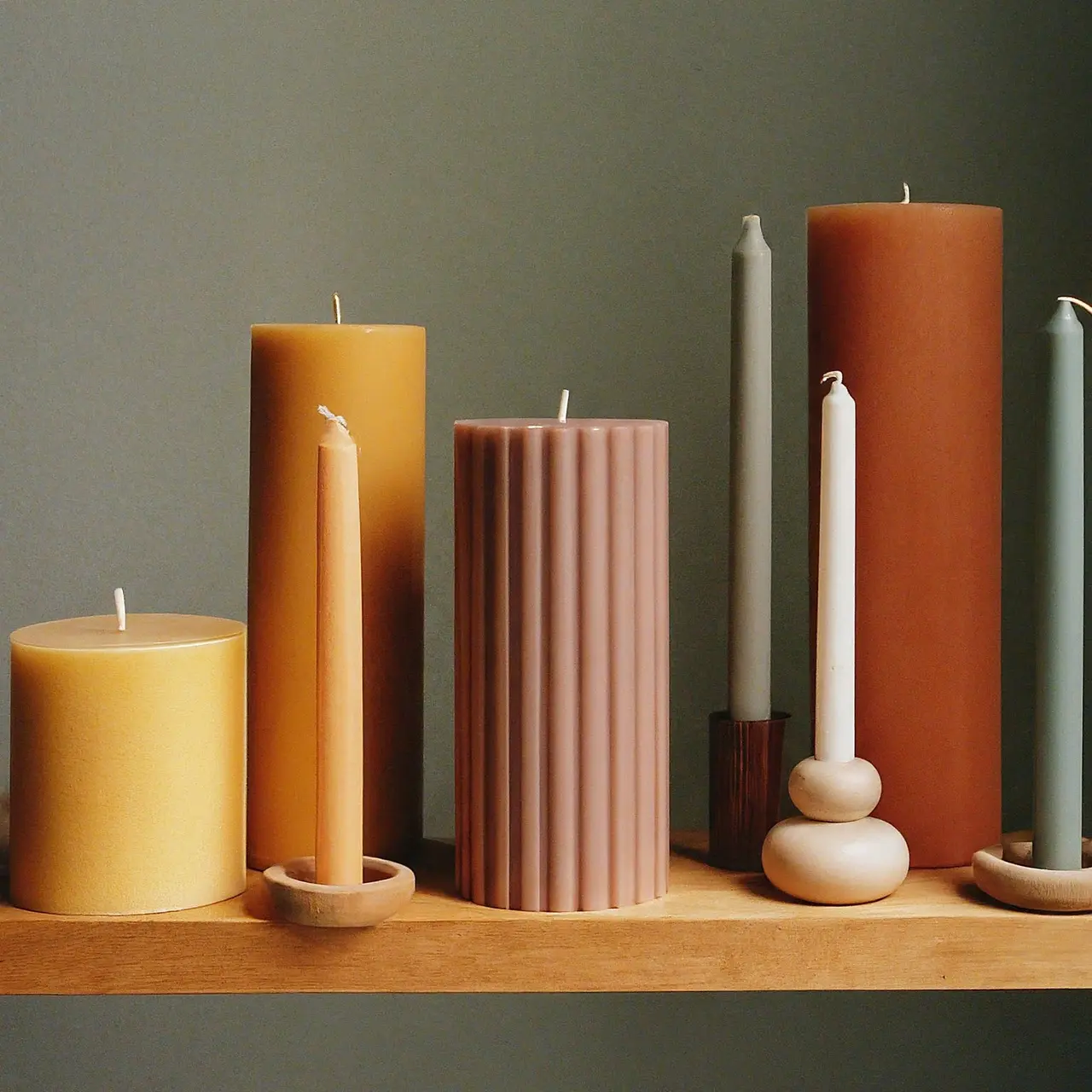 Candles of various sizes and colors on a wooden shelf. 35mm stock photo