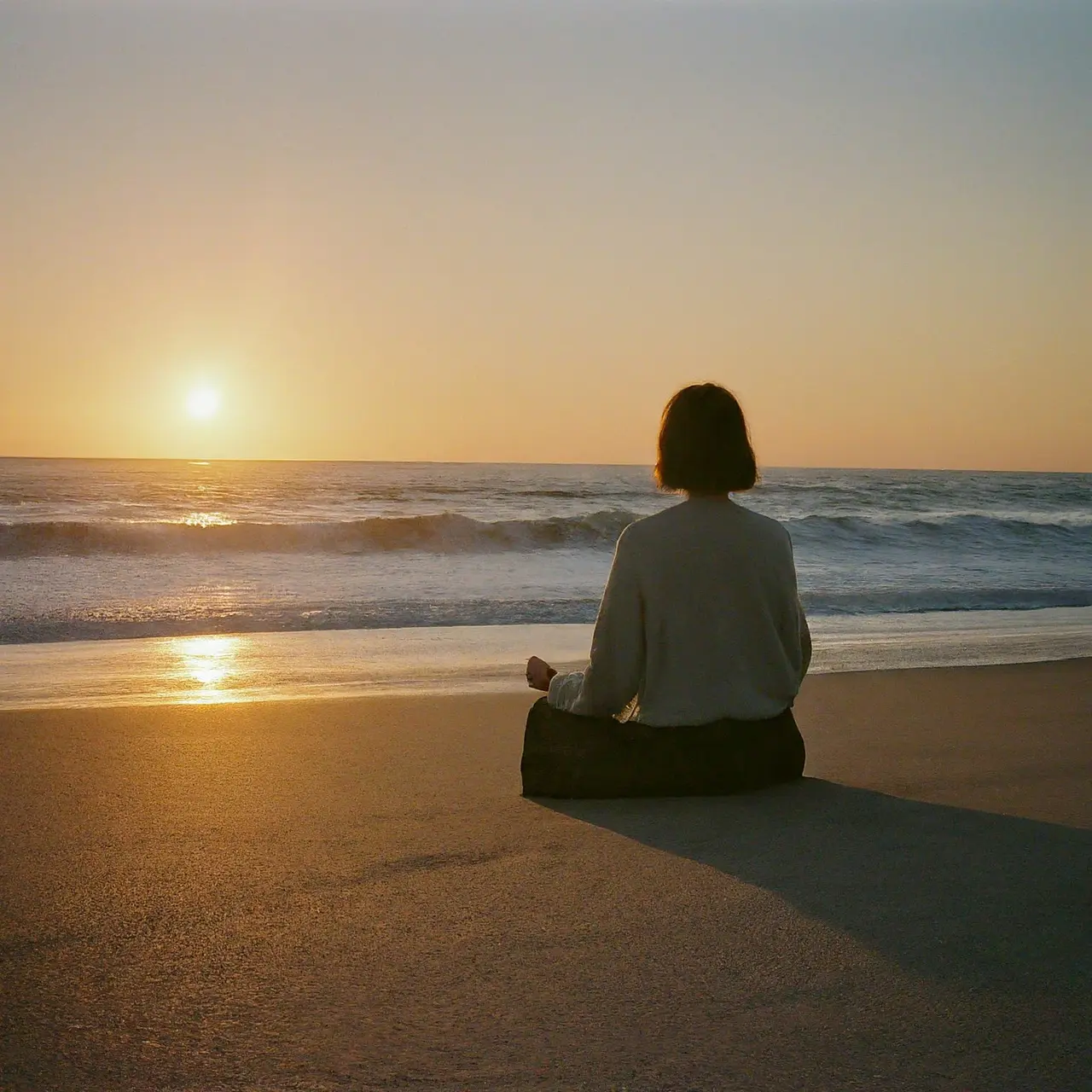 Une personne en méditation sur une plage au coucher du soleil. 35mm stock photo