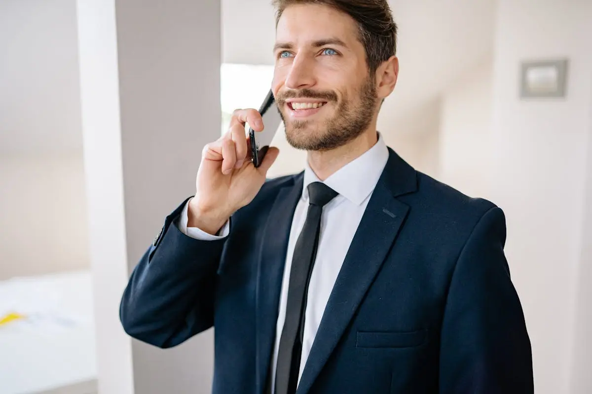 Confident businessman in suit making a phone call indoors, smiling.