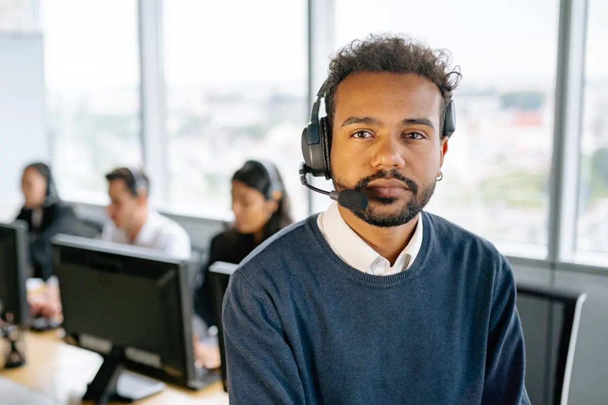 Confident call center agent wearing headset in modern office setting.