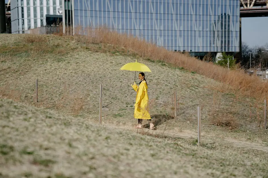 A Woman in Yellow Coat Walking while Holding a Yellow Umbrella