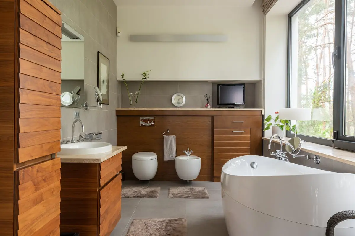 Interior of contemporary bathroom with timber furniture and white sink near mirror in daytime