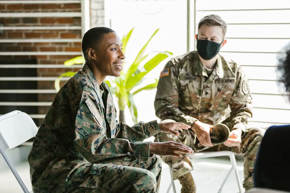 Soldiers in military uniforms discussing during a therapy session indoors.