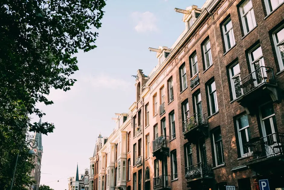 Elegant brick apartment buildings with tree-lined street in soft daylight.