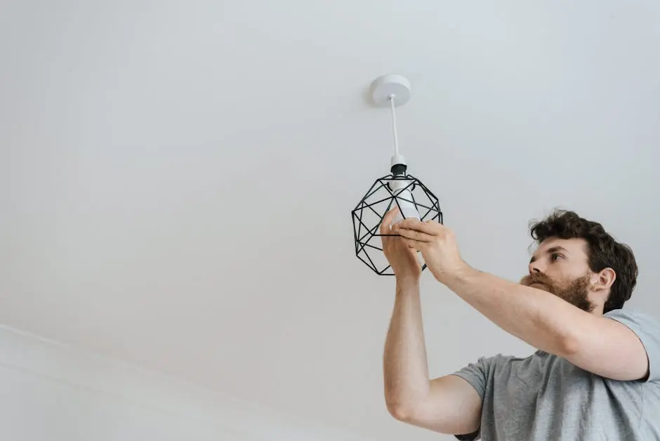 A professional electrician skillfully installing a modern geometric ceiling lamp indoors.