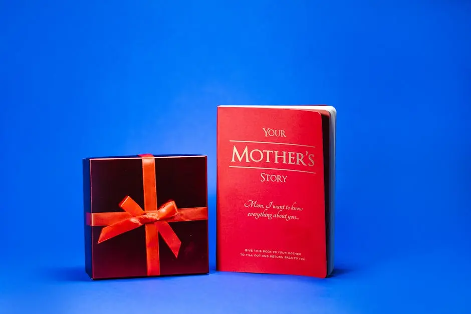 Close-Up Shot of a Book and a Red Gift Box on a Blue Surface