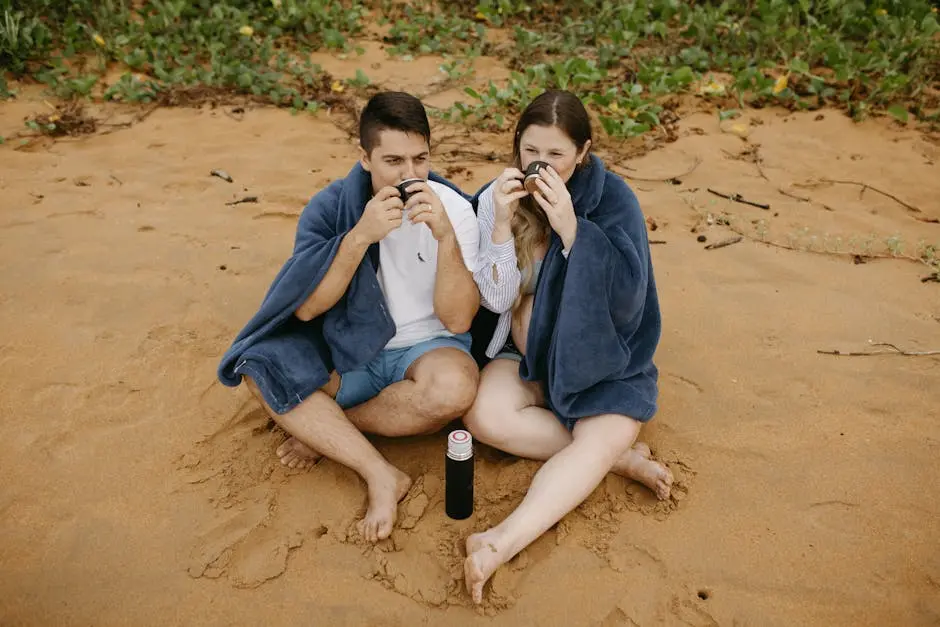 Young couple enjoying hot drinks on a sandy beach