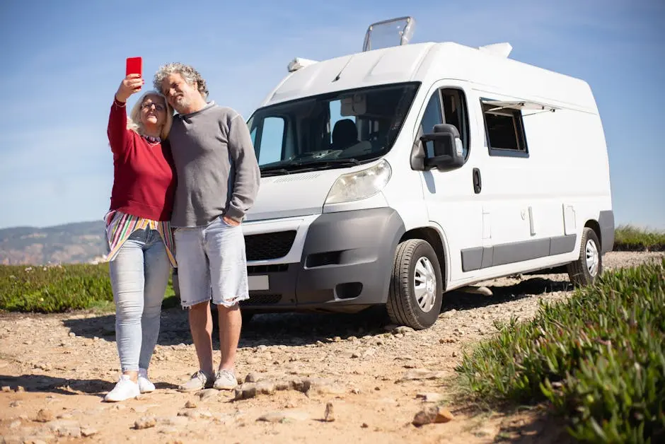 Senior couple enjoying a road trip in Portugal, capturing a selfie beside their RV.