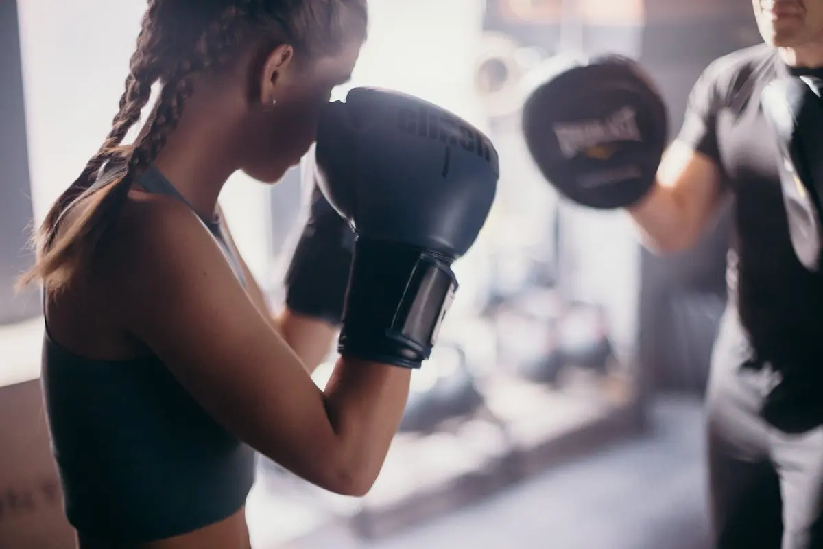 Woman in Black Tank Top Wearing Black Boxing Gloves