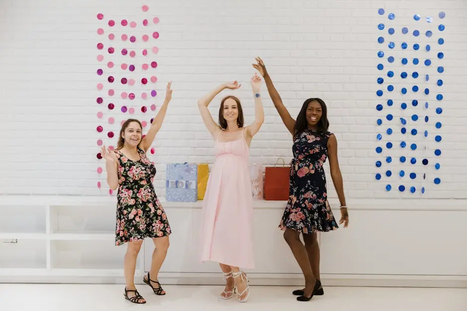 Three women in colorful dresses joyfully celebrating indoors with raised hands.