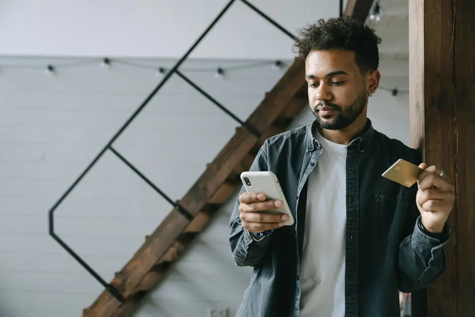 Man Holding Cellphone and a Credit Card