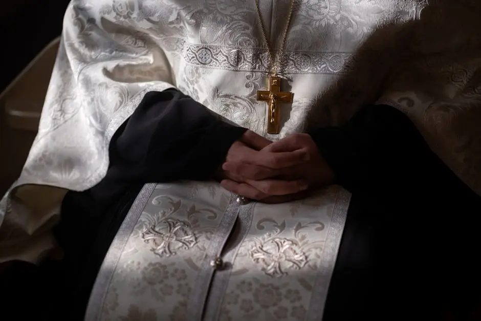 Intimate close-up of orthodox priest’s hands in traditional religious robes, highlighting the intricate fabric and crucifix.