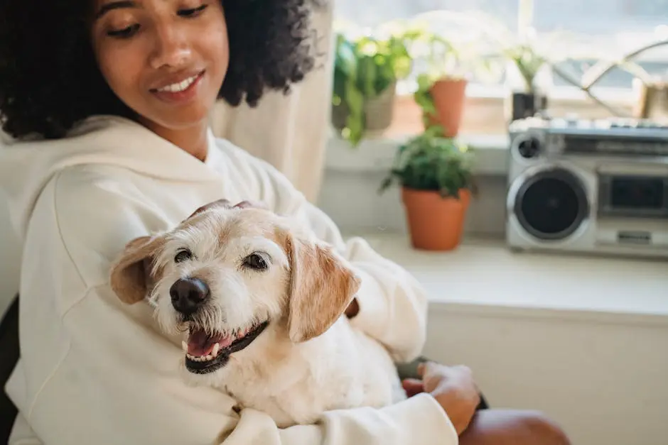 A smiling woman in a cozy hoodie embraces her happy dog indoors, surrounded by plants.