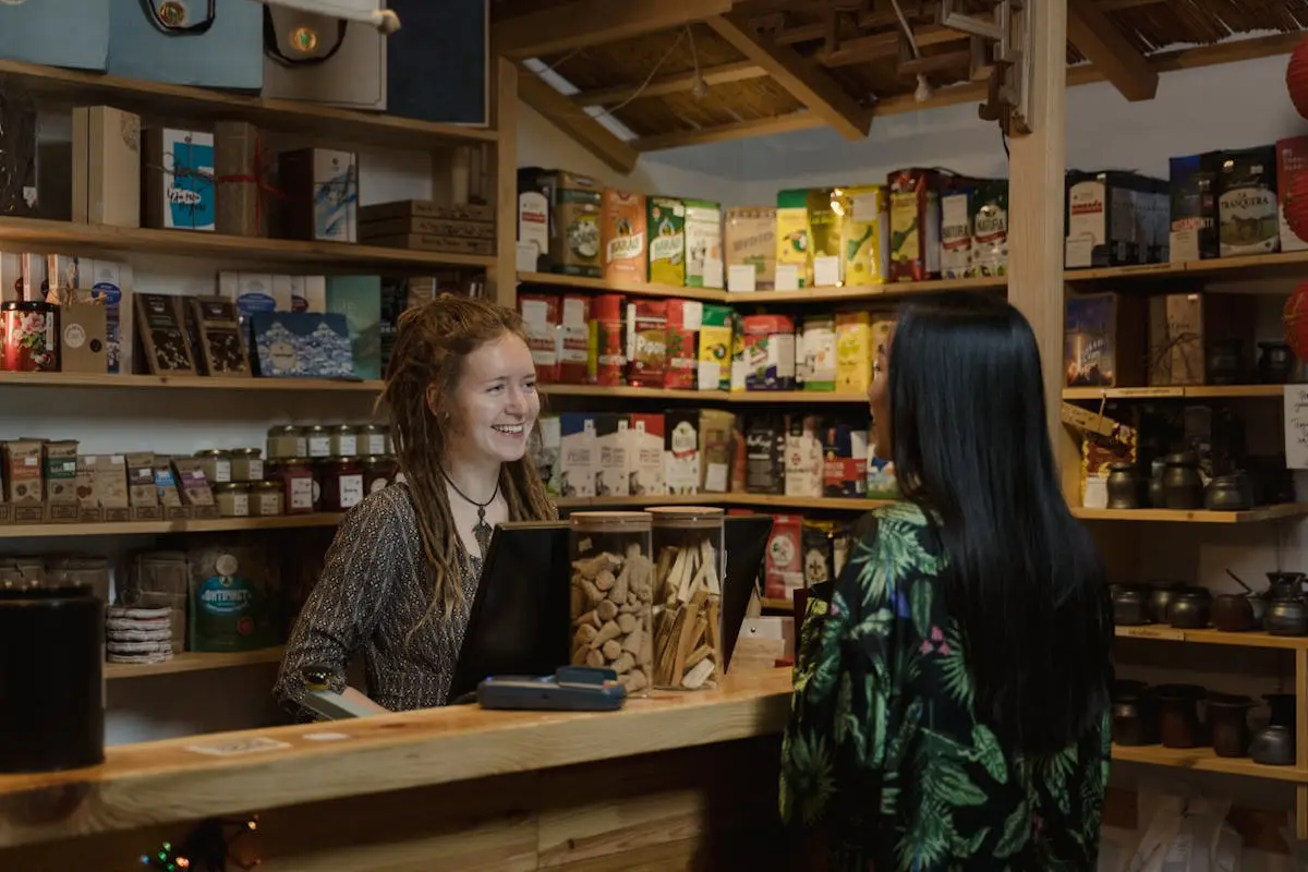 Friendly shopkeeper assisting a customer in a cozy, well-stocked store environment.