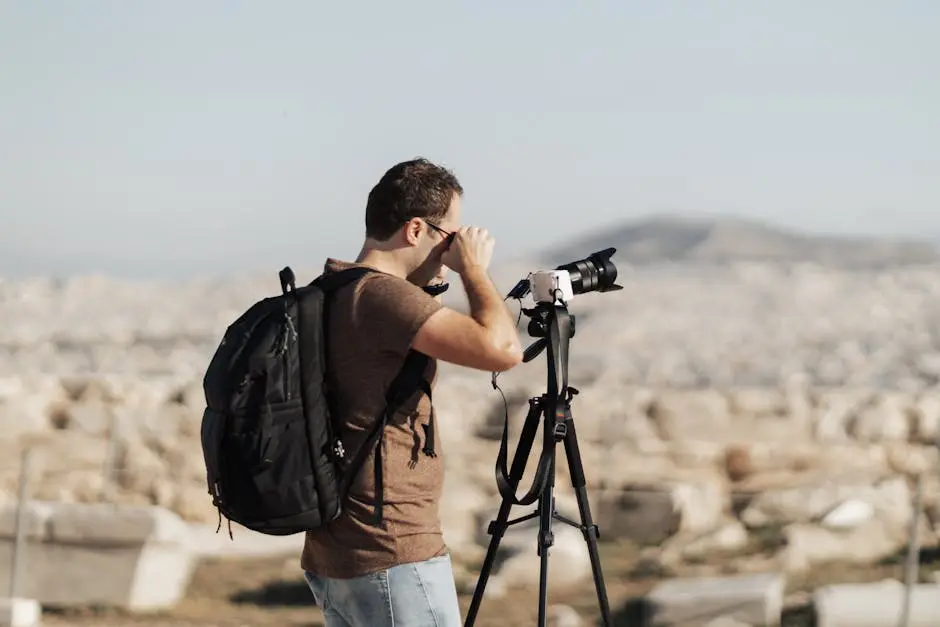 A focused photographer takes pictures outdoors with a DSLR camera on a tripod.