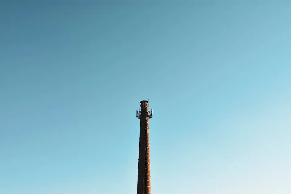 Tall industrial chimney against a clear blue sky, perfect for industry themes.