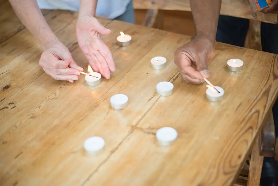 People Lighting Up Tea Candles On Wooden Table