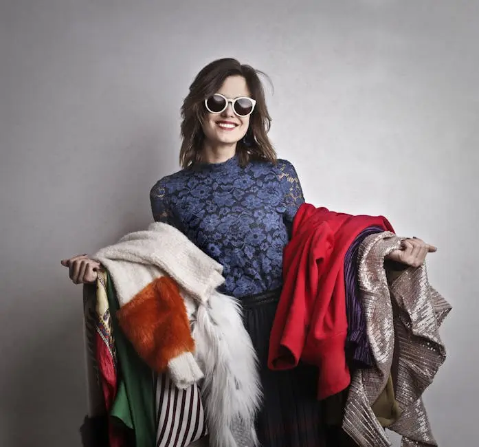 Elegant woman in sunglasses holding a variety of colorful outerwear, smiling at the camera.