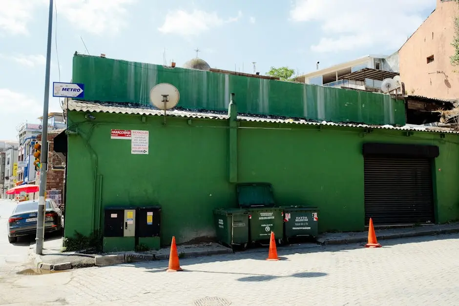 Street view of a vibrant green building with a dumpster on a sunny day.