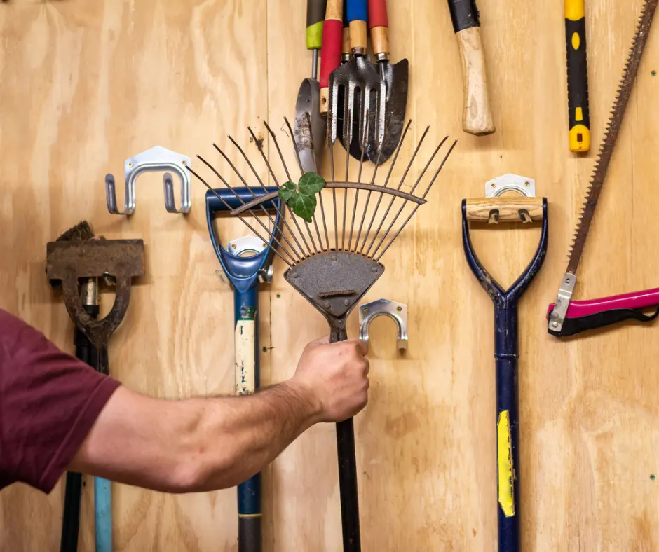 organized garage, man's arm holding rake to organize