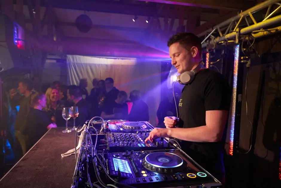 A lively DJ mixes music at a nightclub event, surrounded by a partying crowd, with vivid lights and sound equipment.