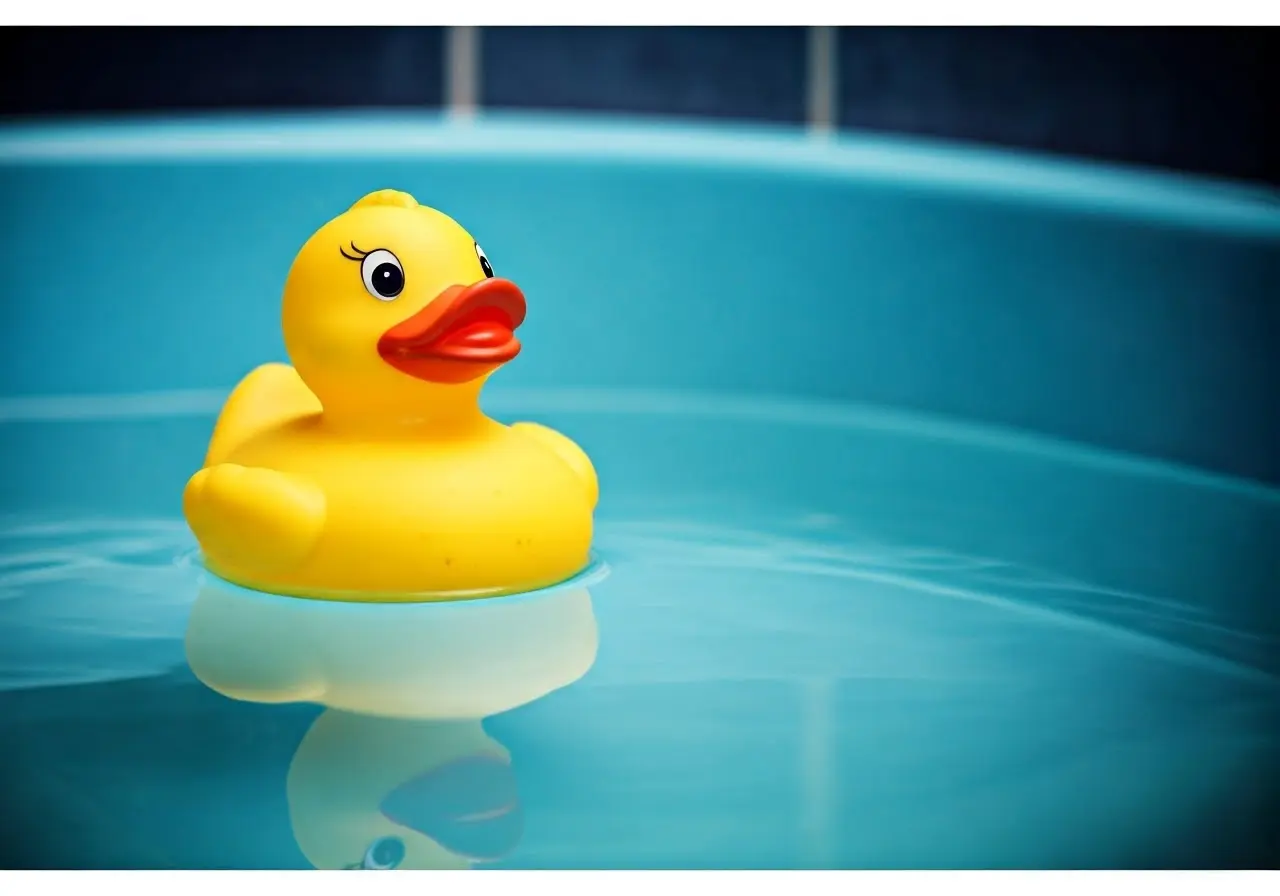 A rubber duck floating in a baby bathtub. 35mm stock photo